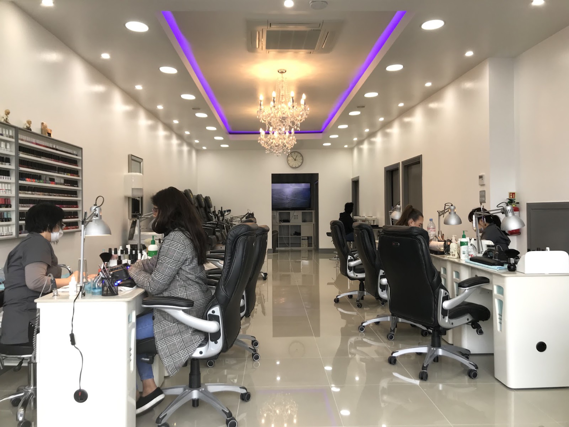 Inside Anna Nails Beauty — bright manicure and pedicure stations, a crystal chandelier and a wall of polish shades